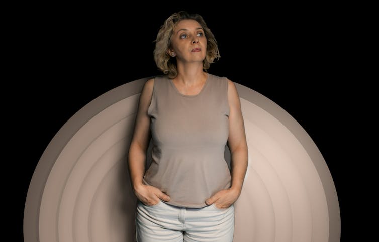 Una mujer con cabello gris frente a un círculo beige sobre un fondo negro
