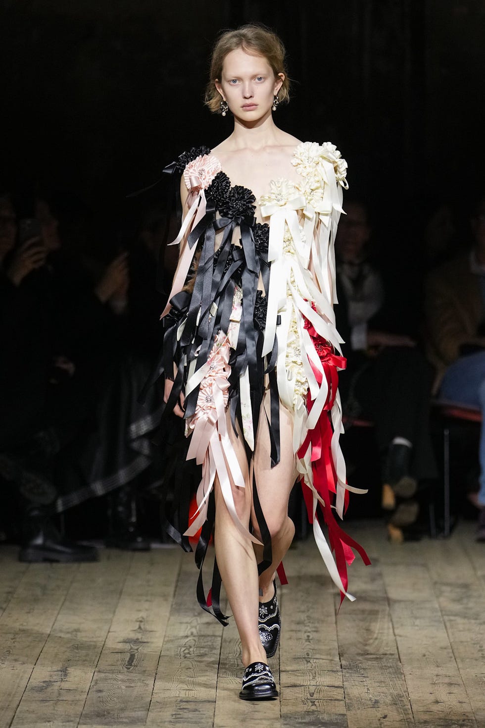 Modelo en la pasarela mostrando un traje adornado con cintas y flores Modelo en la pasarela mostrando un traje adornado con cintas y flores