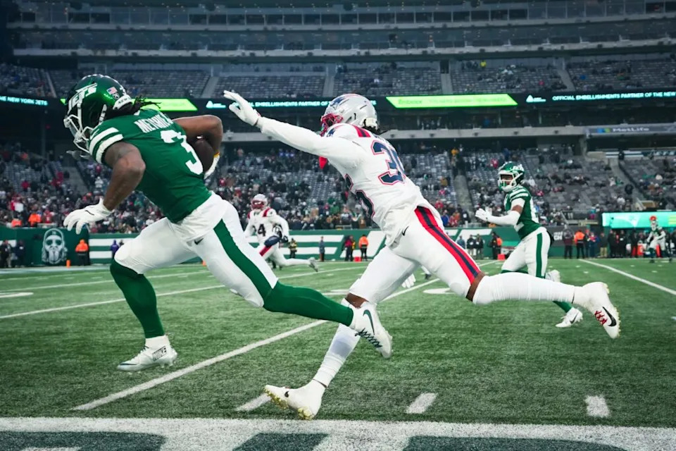 El receptor ancho de New York Jets John Metchie III (3) hace correr la pelota mientras el seguro de los New England Patriots John Saunders Jr. (23) defiende durante un partido en el MetLife Stadium, el 28 de diciembre de 2025, East Rutherford, NJ, EE.UU.
