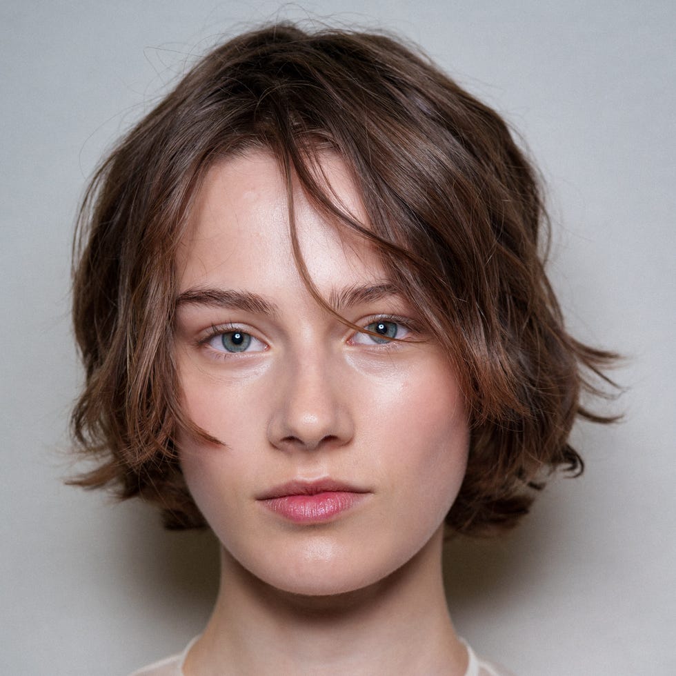 Una persona con rasgos faciales oscurecidos que lleva una pieza floral Una persona con rasgos faciales oscurecidos que lleva una pieza floral